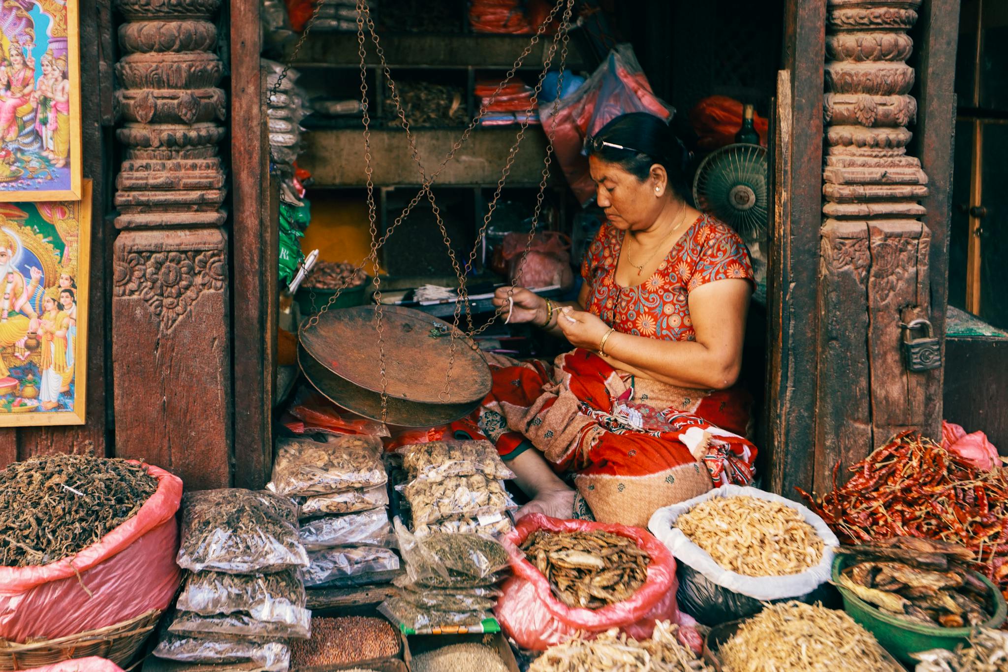 A woman vendor selling assorted spices at a vibrant market stall.